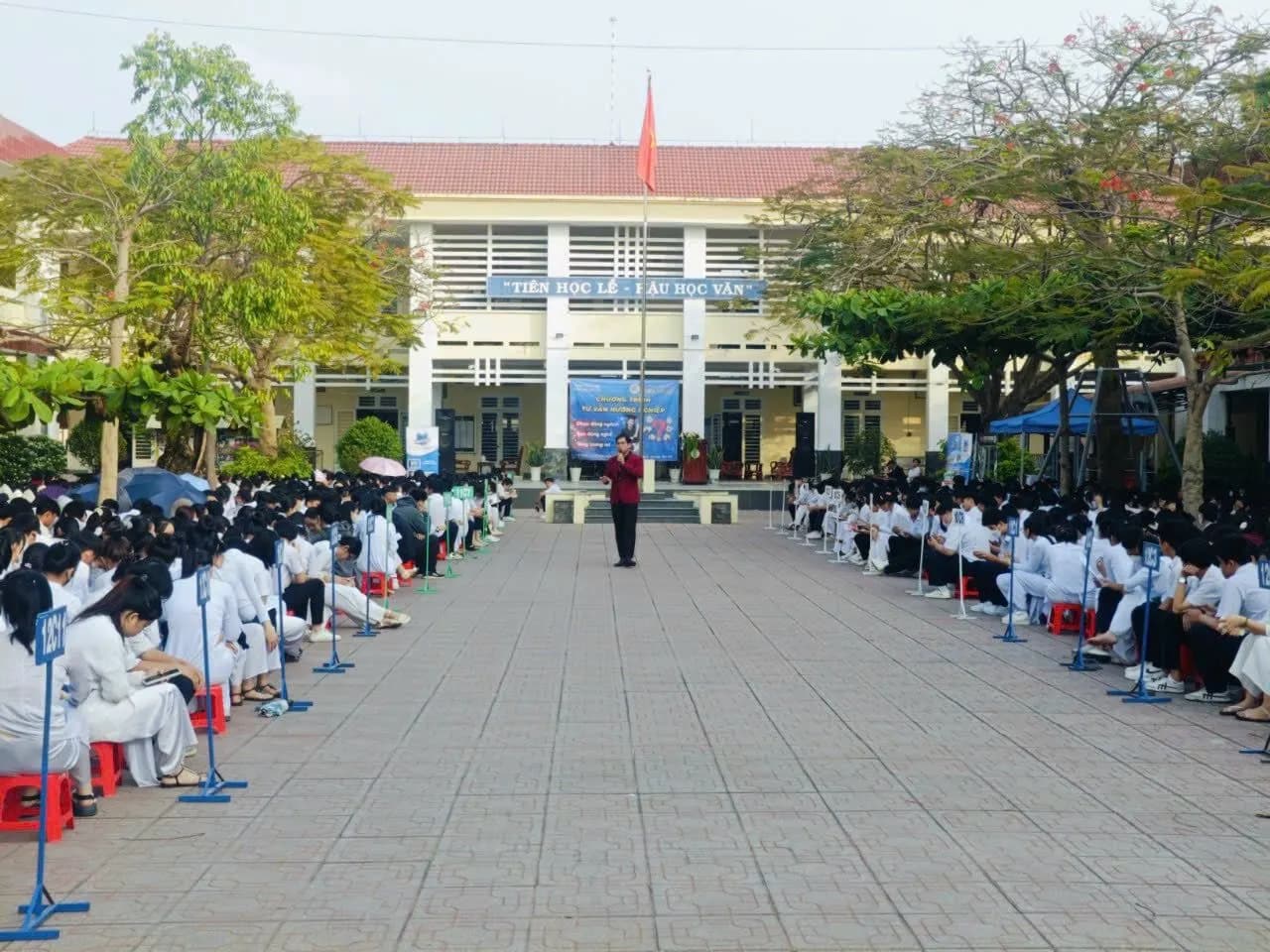 Học sinh ngồi thành hai dãy hai bên lối đi sân trường, nghe tư vấn hướng nghiệp
