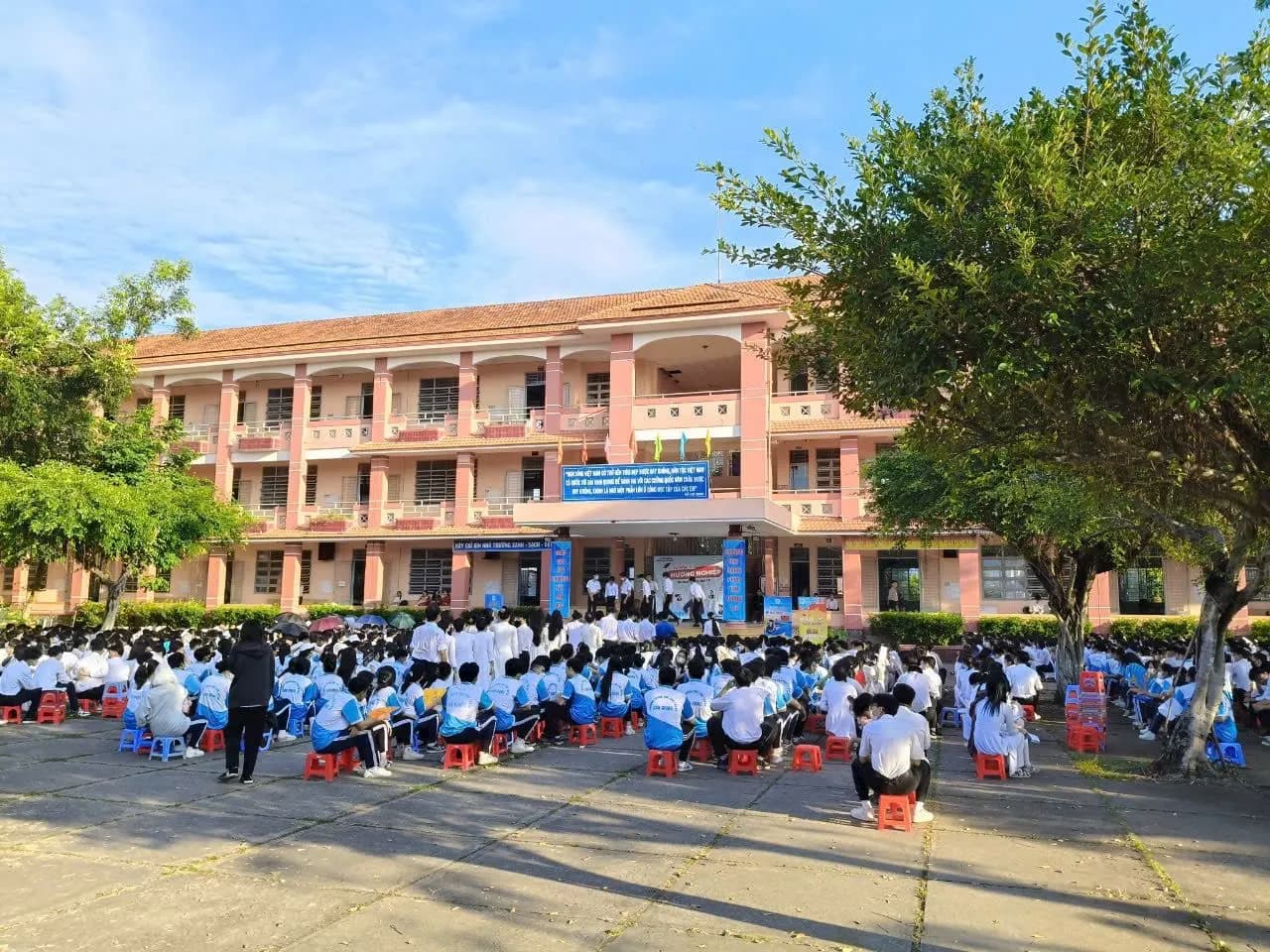 Học sinh ngồi kín sân trường dưới trời xanh, cùng hướng về sân khấu